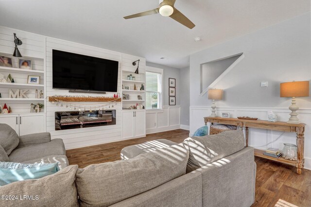 living room featuring dark hardwood / wood-style floors, a large fireplace, and ceiling fan