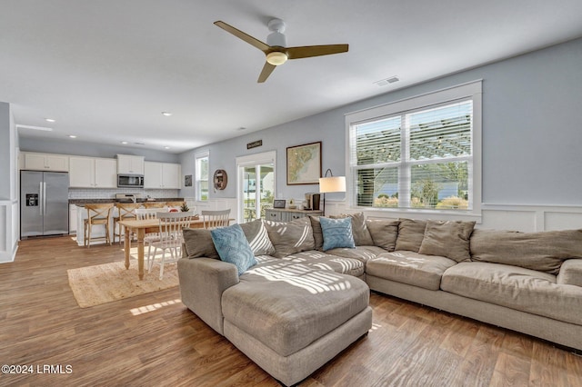 living room with ceiling fan and light hardwood / wood-style flooring