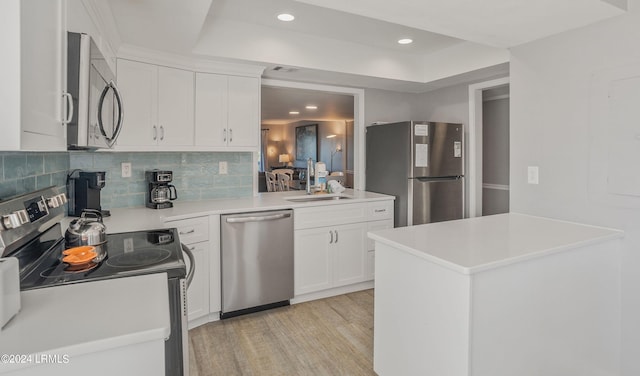 kitchen with sink, light wood-type flooring, a raised ceiling, stainless steel appliances, and white cabinets