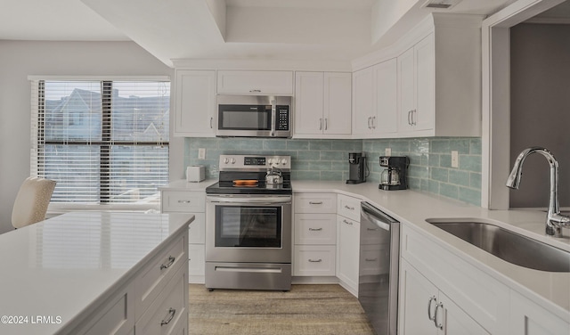 kitchen with white cabinetry, sink, stainless steel appliances, and light hardwood / wood-style floors