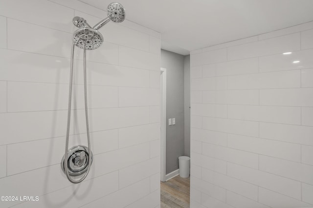 bathroom with tiled shower and hardwood / wood-style floors