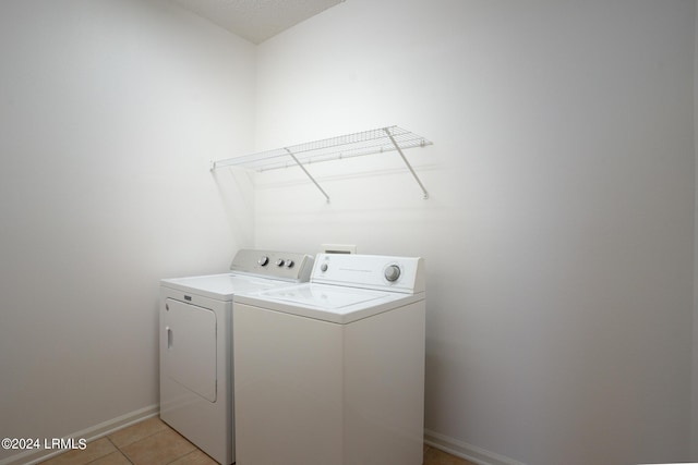 washroom with light tile patterned floors and washing machine and dryer