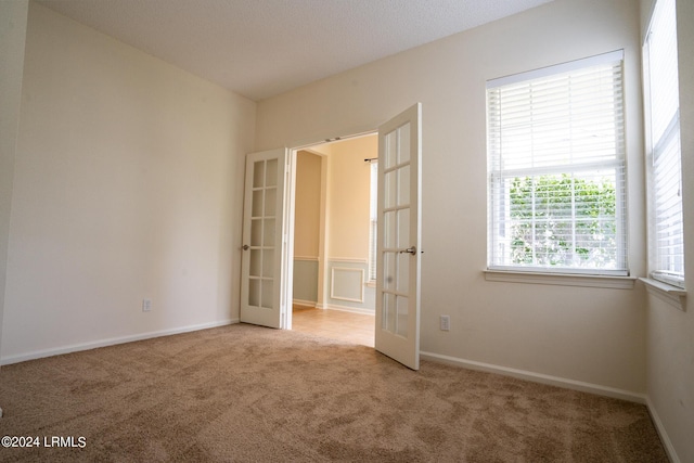 spare room with french doors and light carpet