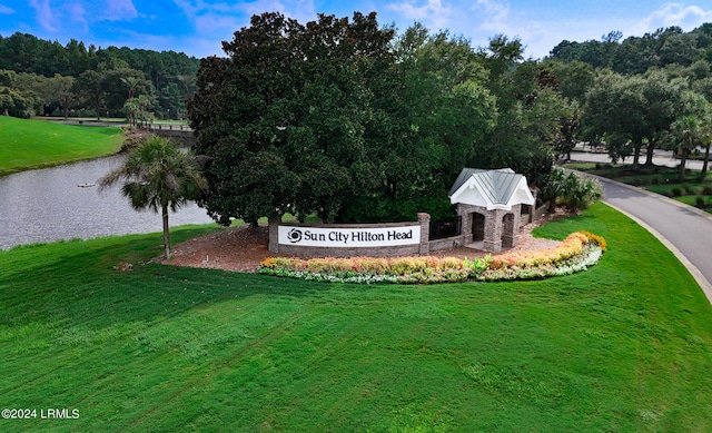 community sign featuring a water view and a yard