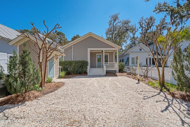 view of front of house with gravel driveway, fence, and covered porch