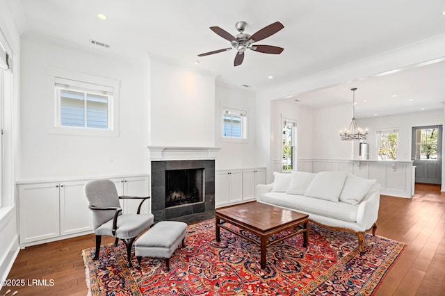 living area featuring a wainscoted wall, visible vents, wood-type flooring, and a tile fireplace