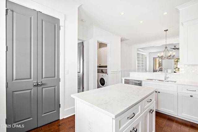 kitchen featuring a sink, washer / clothes dryer, stainless steel dishwasher, and dark wood-style floors