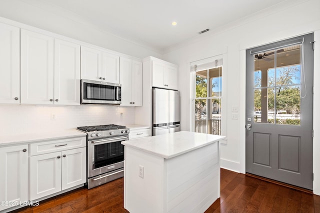 kitchen featuring stainless steel appliances, dark wood-type flooring, visible vents, and decorative backsplash