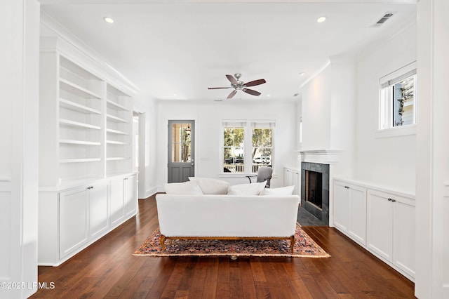 living area featuring visible vents, recessed lighting, a fireplace, dark wood-type flooring, and crown molding