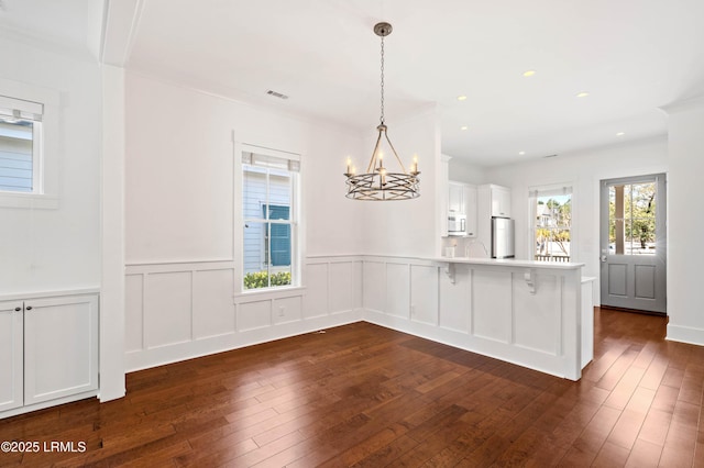 unfurnished dining area featuring dark wood finished floors, recessed lighting, and a chandelier