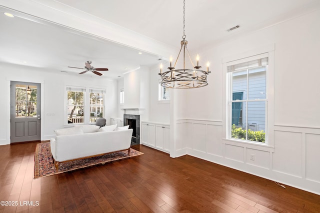 living room featuring visible vents, a wainscoted wall, dark wood finished floors, and a fireplace