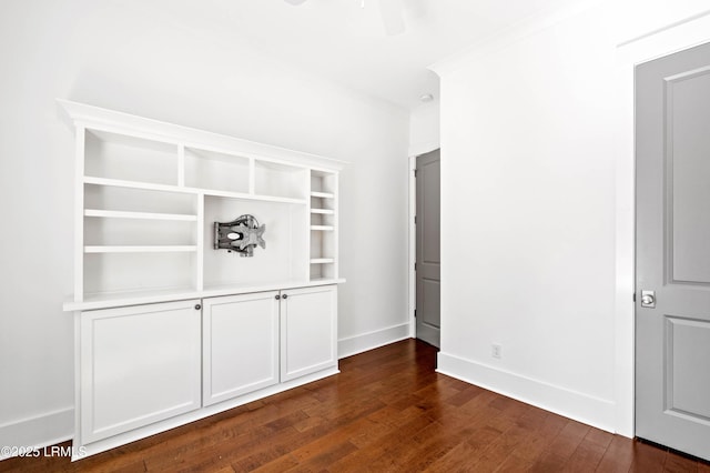 interior space featuring baseboards, ceiling fan, dark wood-style flooring, and crown molding