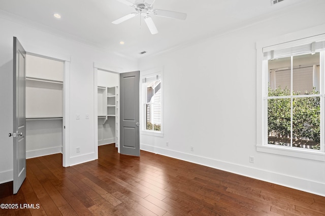 unfurnished bedroom featuring baseboards, multiple closets, visible vents, and hardwood / wood-style flooring