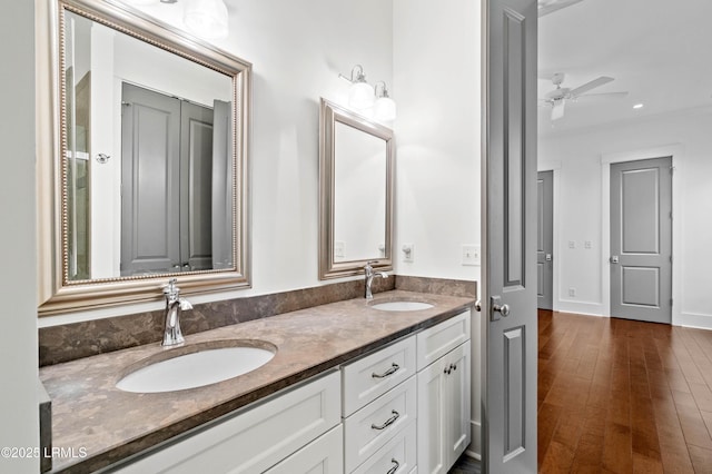 bathroom with a sink, a ceiling fan, wood finished floors, and double vanity