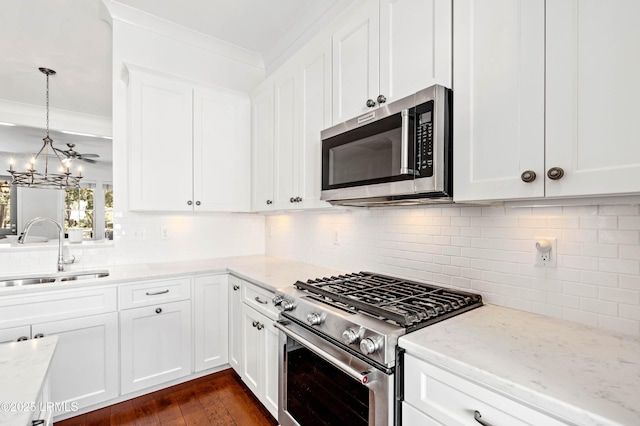 kitchen with ornamental molding, appliances with stainless steel finishes, light stone countertops, and a sink