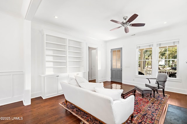 sitting room featuring built in features, dark wood finished floors, recessed lighting, ceiling fan, and a decorative wall