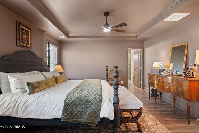 bedroom with ceiling fan, ornamental molding, a tray ceiling, and hardwood / wood-style floors