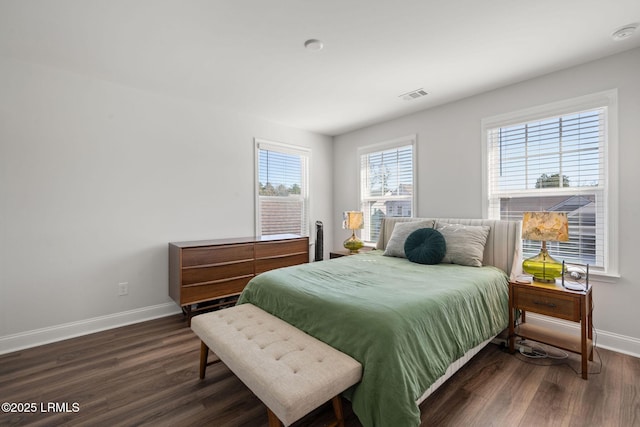 bedroom with dark wood-style floors, visible vents, and baseboards