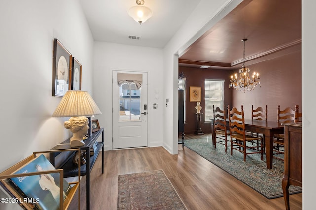 entryway with baseboards, wood finished floors, visible vents, and a chandelier