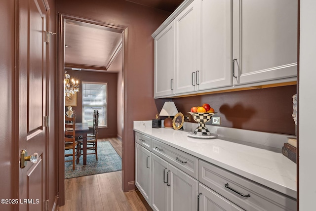 bar with white cabinetry, light stone counters, and light wood-type flooring