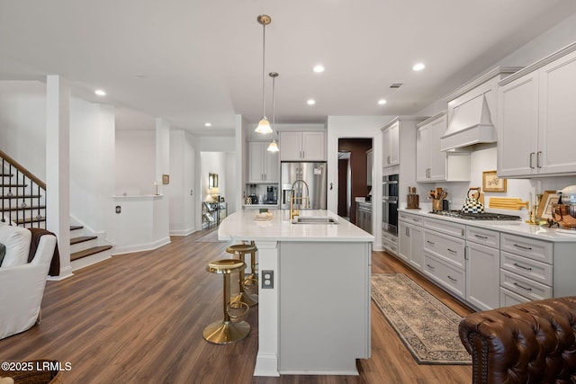 kitchen with open floor plan, appliances with stainless steel finishes, dark wood-type flooring, and premium range hood