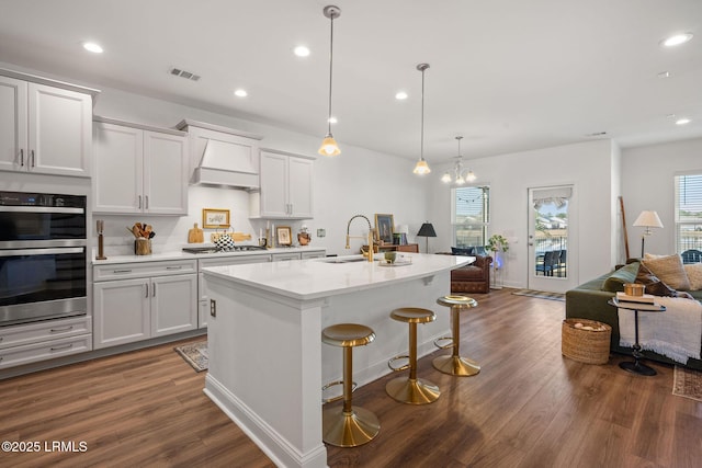 kitchen with premium range hood, dark wood-style flooring, stainless steel appliances, a sink, and open floor plan