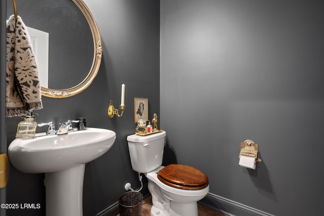 bathroom with toilet, baseboards, and a sink