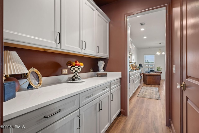 kitchen featuring light stone counters, visible vents, light wood finished floors, recessed lighting, and white cabinets