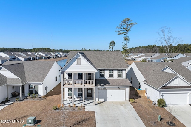 view of front facade featuring a residential view, a balcony, roof with shingles, and driveway