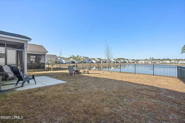 view of yard featuring a patio area, a sunroom, a fenced backyard, and a water view