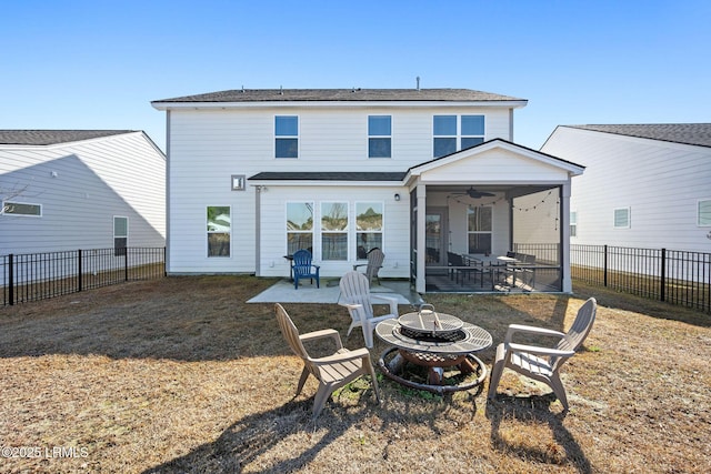 rear view of property with a ceiling fan, a fenced backyard, a fire pit, a patio area, and a lawn