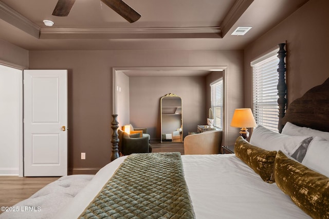 bedroom featuring hardwood / wood-style floors, a tray ceiling, ornamental molding, and ceiling fan