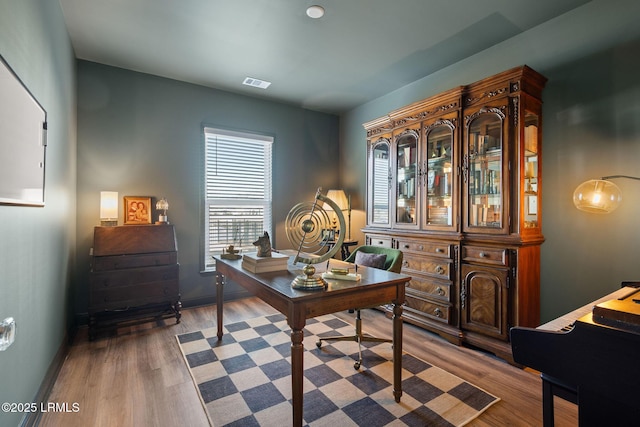 home office featuring wood finished floors, visible vents, and baseboards