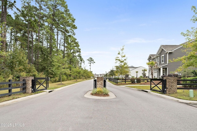 view of street with a gate, curbs, a residential view, and a gated entry