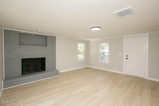 unfurnished living room featuring ornamental molding, a fireplace, and light hardwood / wood-style floors