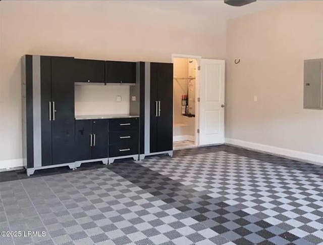kitchen with light countertops, baseboards, dark cabinetry, and electric panel
