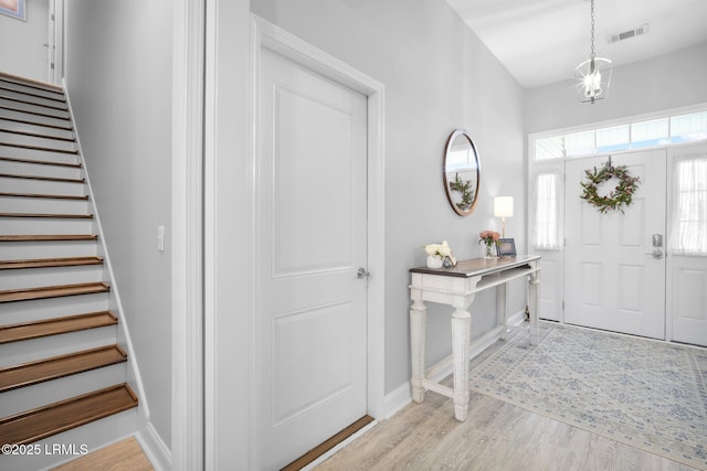 entrance foyer with light wood-type flooring, visible vents, baseboards, and stairs