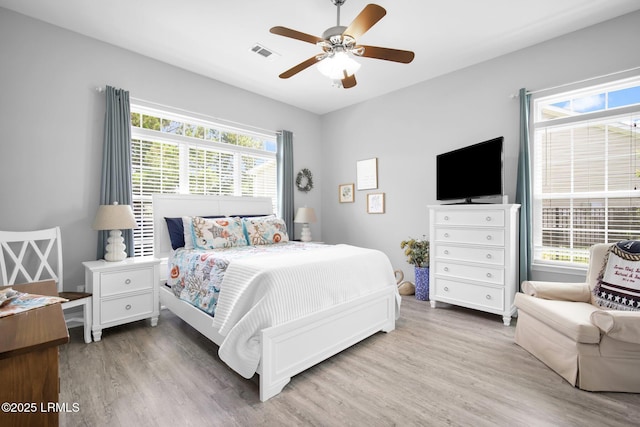 bedroom with hardwood / wood-style flooring, ceiling fan, and multiple windows