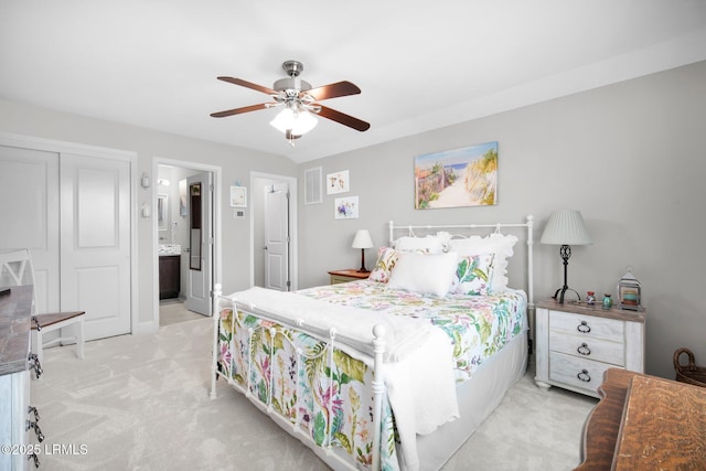 bedroom featuring ceiling fan, light colored carpet, and connected bathroom