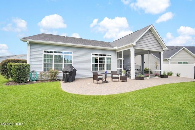 rear view of house featuring a patio, fence, a yard, a sunroom, and a shingled roof