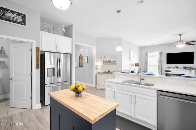 kitchen featuring butcher block countertops, a sink, white cabinets, appliances with stainless steel finishes, and open floor plan