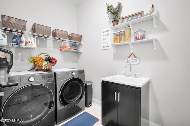 clothes washing area featuring washing machine and clothes dryer, laundry area, baseboards, and a sink