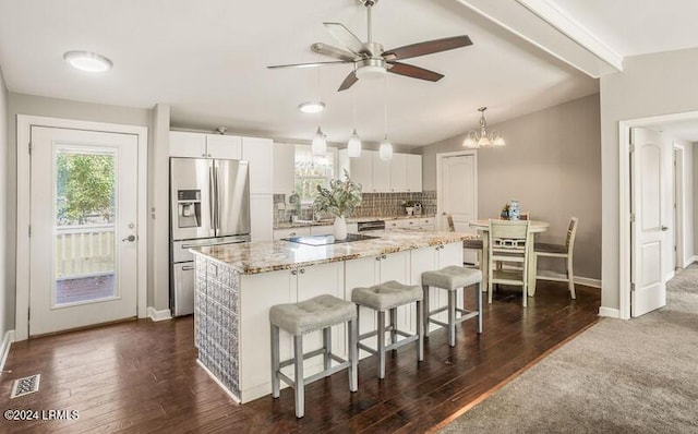 kitchen featuring backsplash, a center island, white cabinets, stainless steel fridge with ice dispenser, and decorative light fixtures