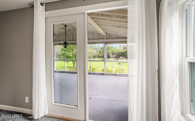 doorway to outside with lofted ceiling and carpet floors