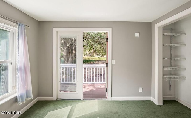 doorway to outside featuring plenty of natural light and dark colored carpet