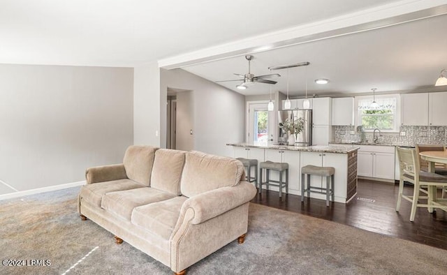 living room featuring ceiling fan, sink, and lofted ceiling with beams