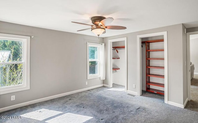 unfurnished bedroom with carpet flooring, two closets, and ceiling fan