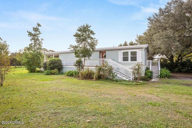 manufactured / mobile home featuring a wooden deck and a front lawn