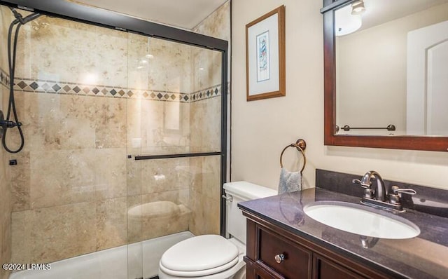 bathroom with vanity, toilet, and a shower with door