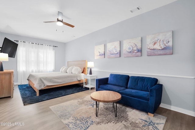 bedroom featuring a ceiling fan, visible vents, wood finished floors, and baseboards